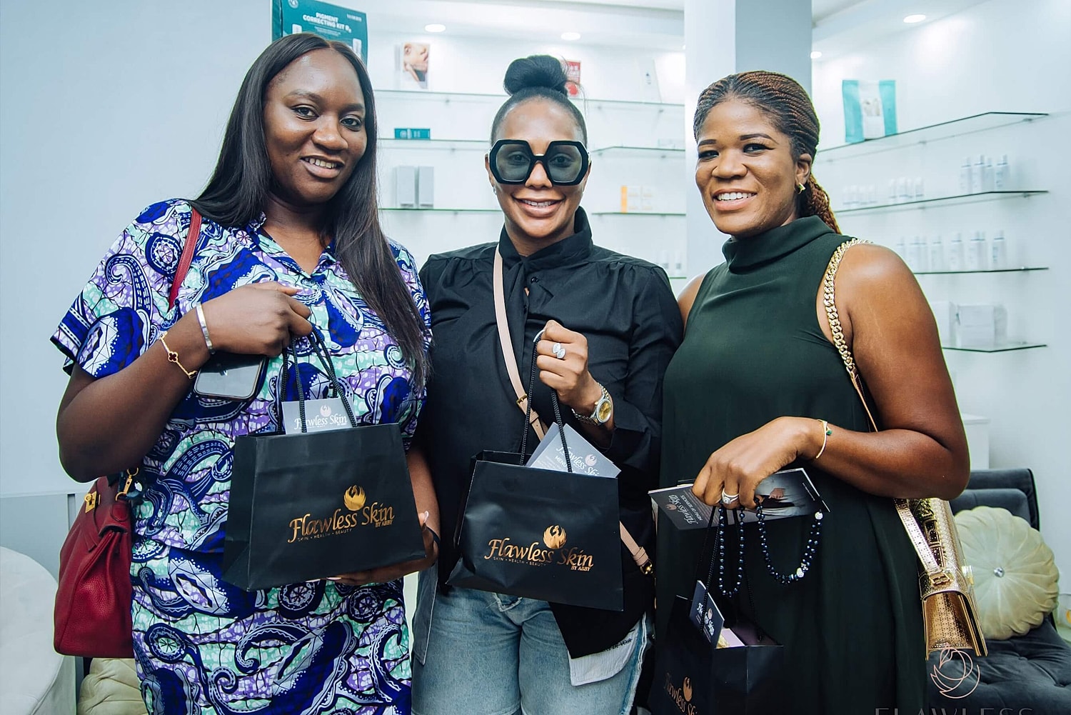 Three women smiling with product bags in hand.