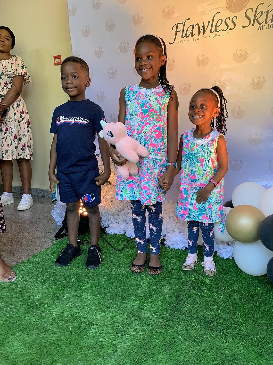 Children with plush toy at event backdrop.