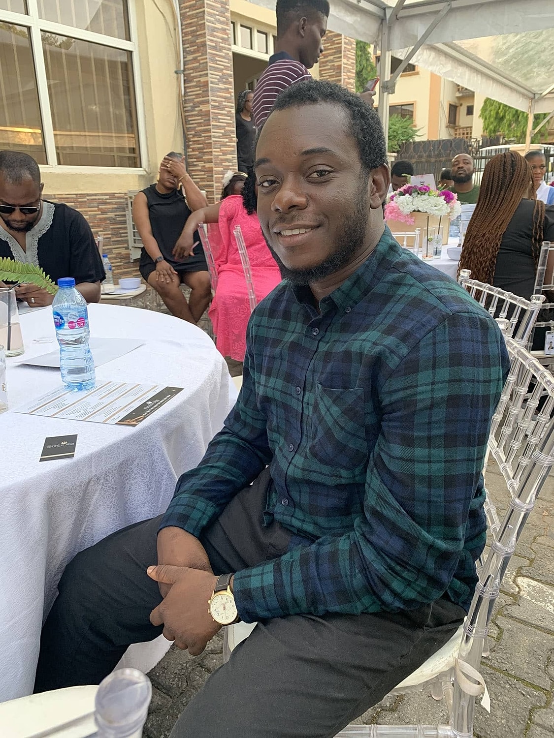 Man smiling at event with people in background.
