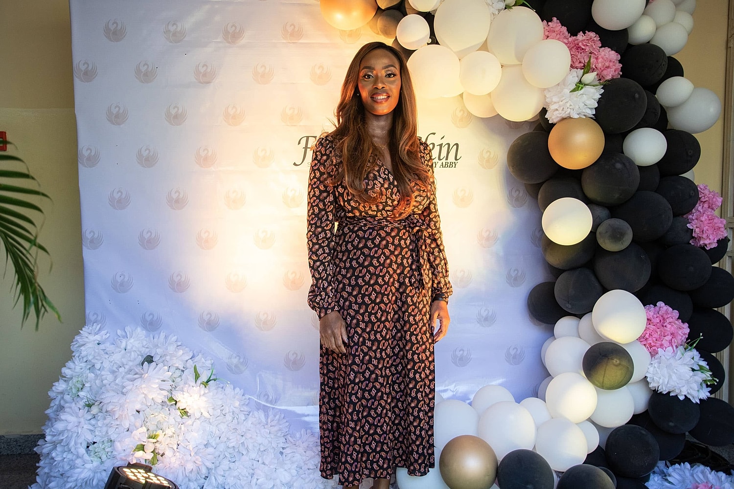 Woman in patterned dress standing by balloon decorations