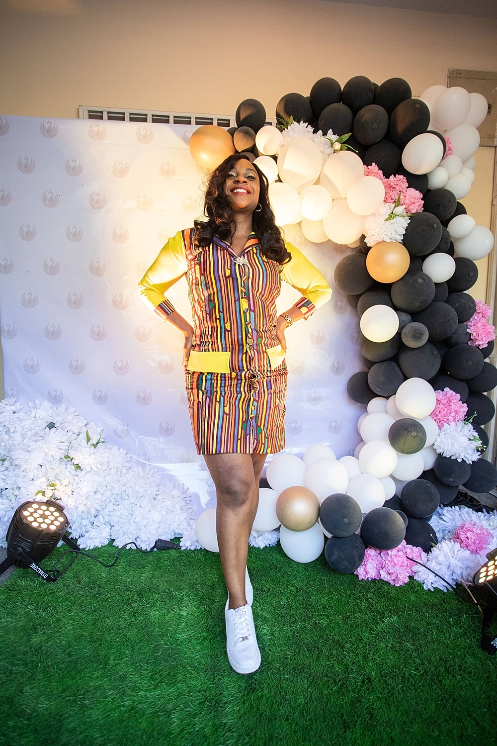 Woman in colorful outfit posing with balloons.