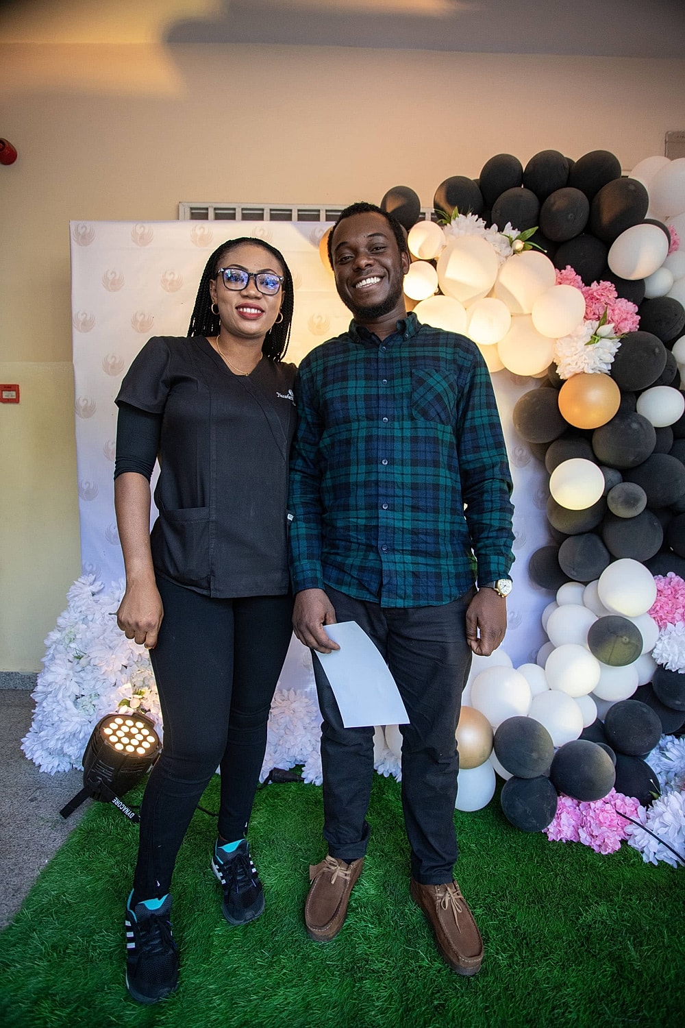 Smiling couple posing near balloon decorations.