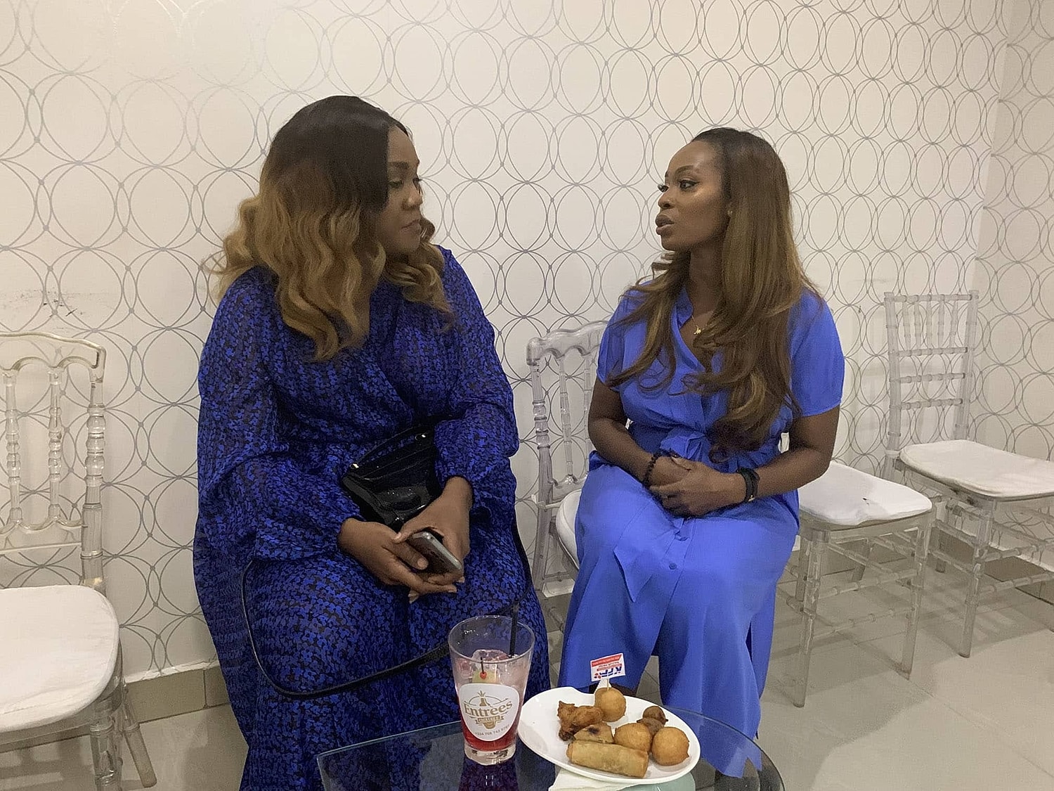 Two women chatting over snacks and drinks.
