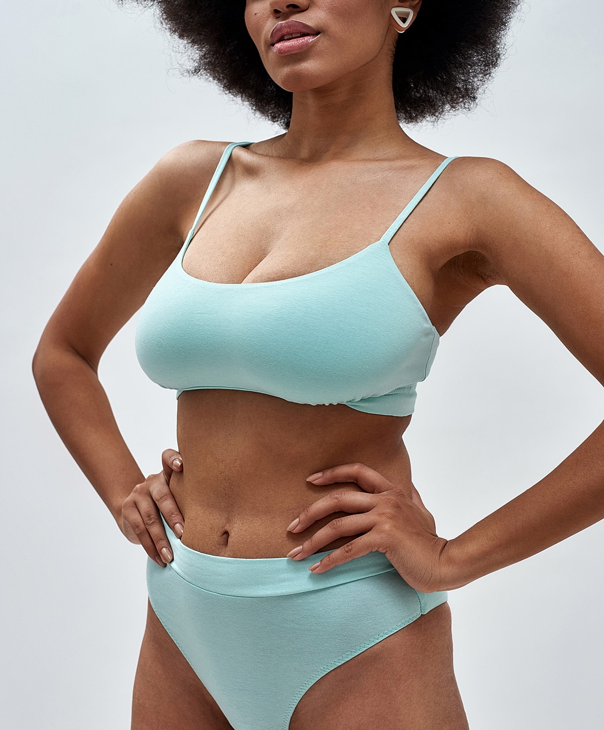 Abuja Labiaplasty model in mint green swimwear, stylish pose.
