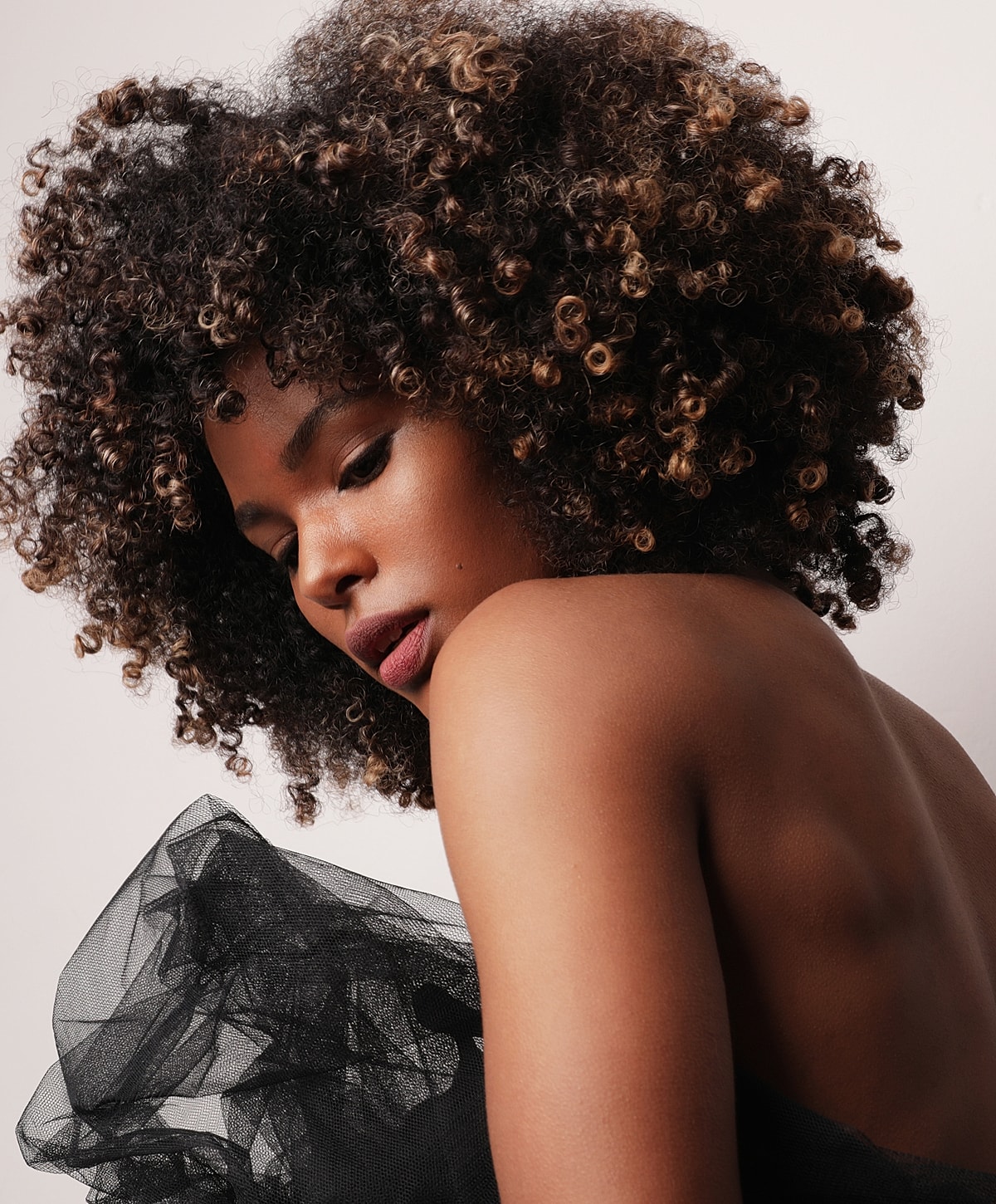 Model with curly hair and black tulle fabric.