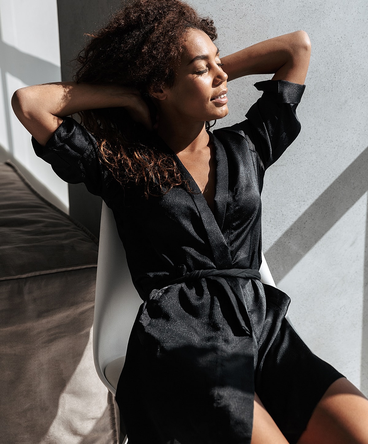 Woman in black outfit relaxing in sunlight.