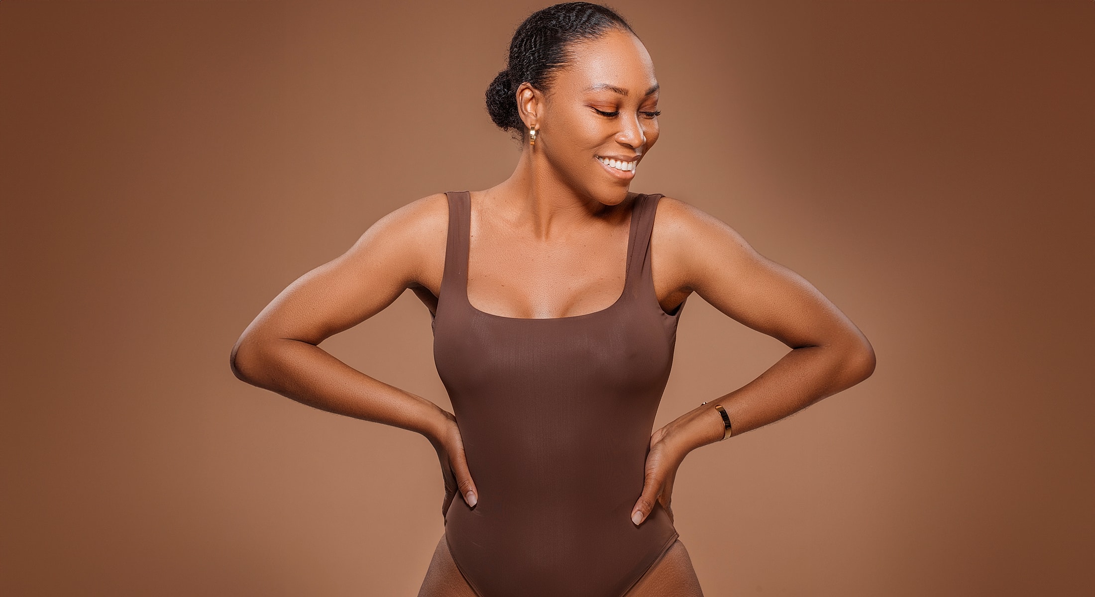 Smiling woman in brown swimsuit against neutral background