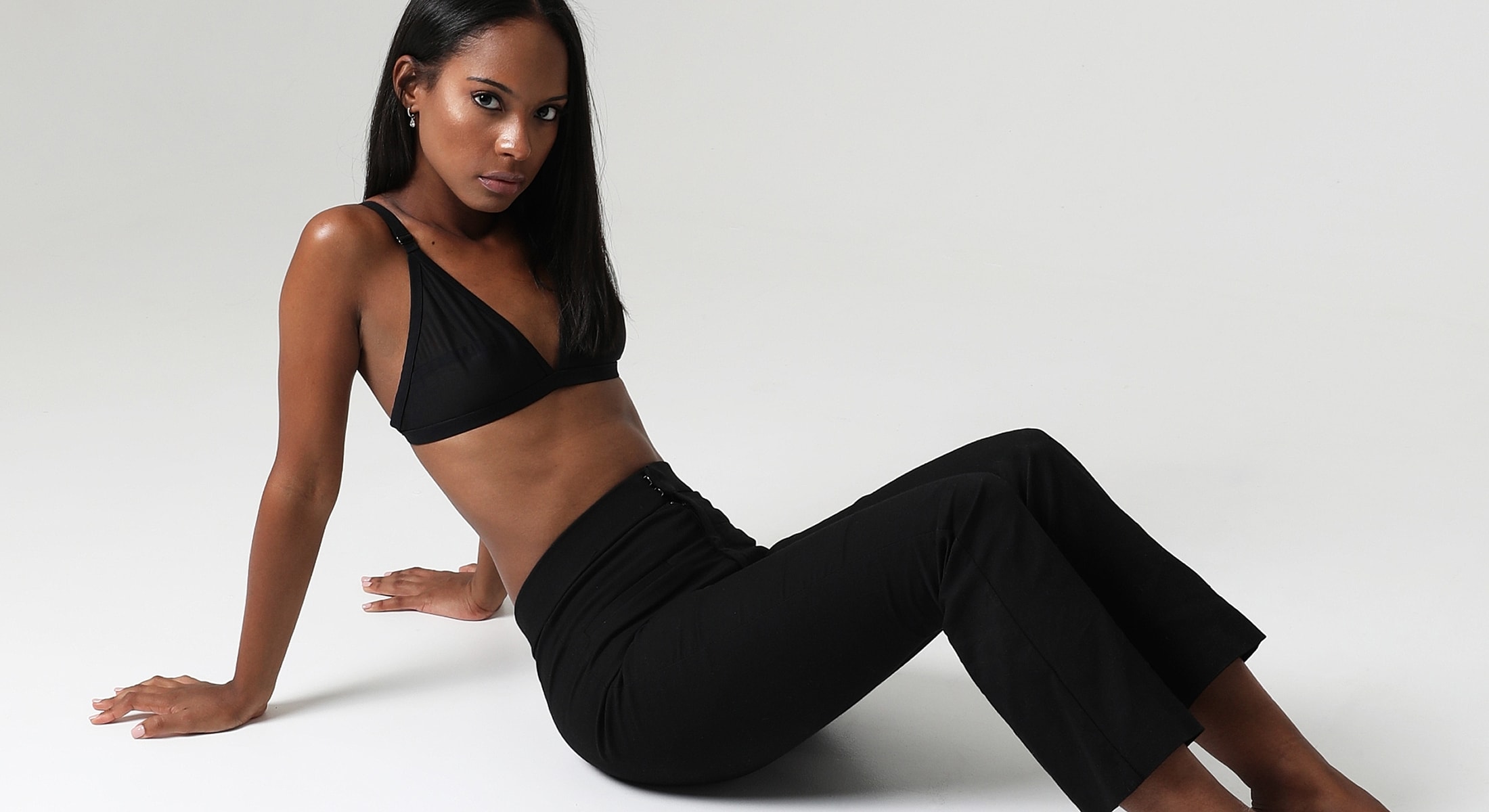 Model sitting in stylish black attire.