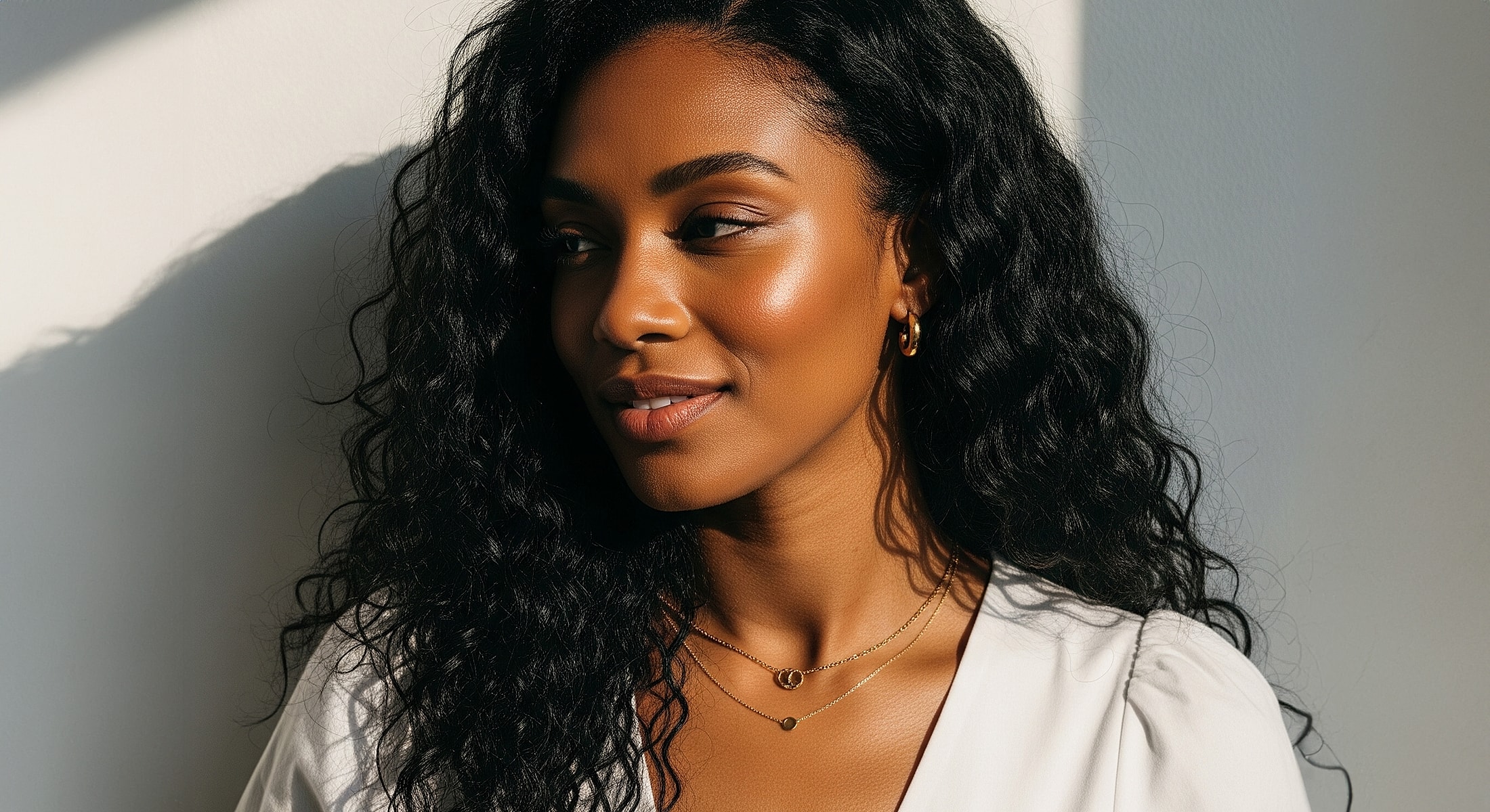Woman with curly hair and layered necklaces.