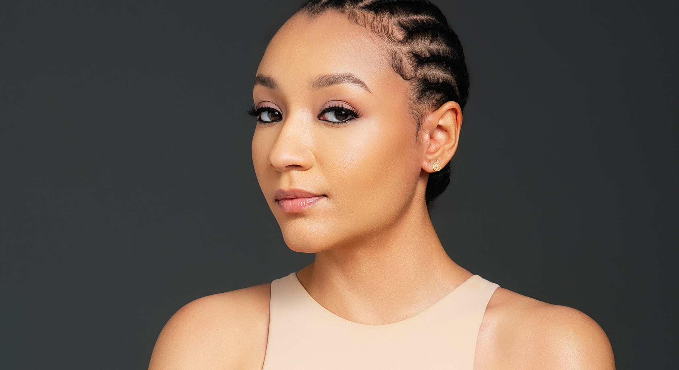 Abuja PDO Thread Lift model with braided hair, neutral backdrop, confident expression.