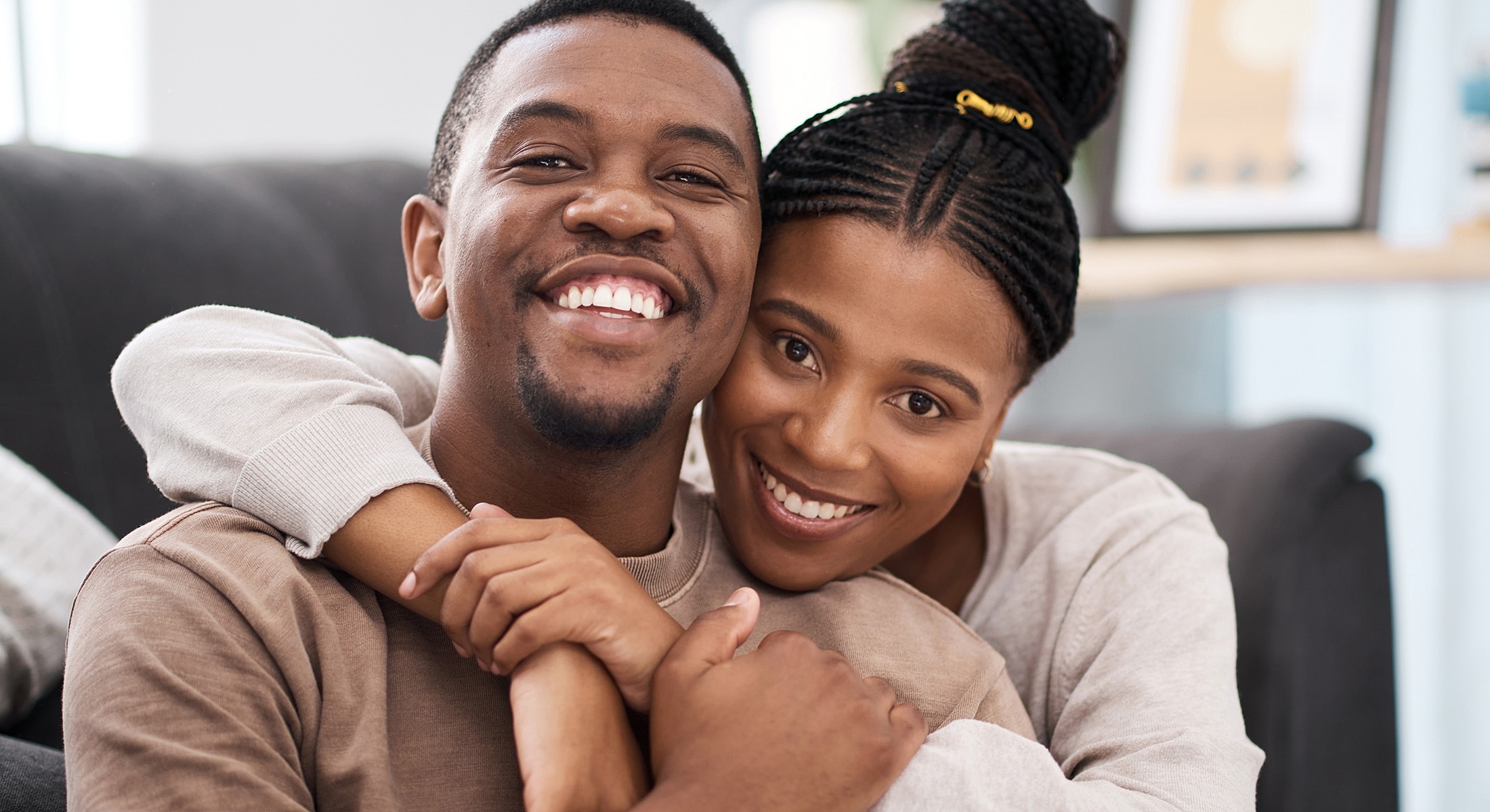 Couple smiling and embracing on a couch.